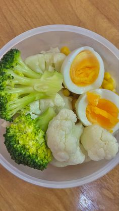 an egg, broccoli and boiled eggs in a bowl on a wooden table