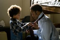 a young boy helping an older man tie his tie