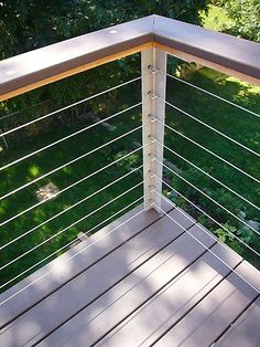 a wooden deck with metal railing and grass in the background