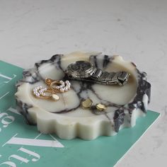 a white and black marble tray with jewelry on it sitting on top of a table