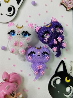 three little stuffed animals sitting next to each other on top of a white table with pink and purple flowers