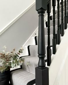 a black and white stair case next to a planter with flowers on the floor