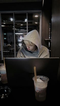 a person sitting in front of a laptop computer on top of a table next to a drink