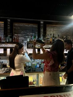 two women are at the bar and one woman is holding a tray in her hand