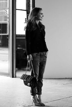 black and white photograph of a woman holding a handbag in front of a building