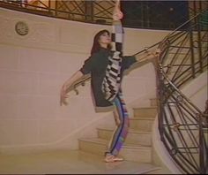 a woman standing on top of a stair case next to a hand rail in front of a spiral staircase