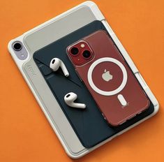 an iphone case with ear buds and headphones attached to it on top of an orange surface