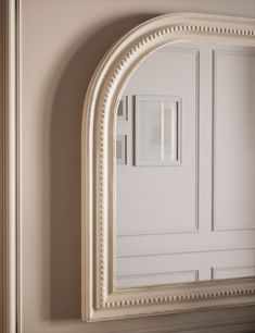 an arched white mirror on the wall