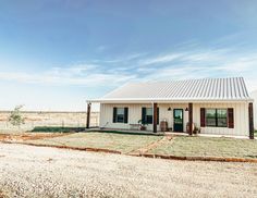 a small white house sitting on top of a dry grass field