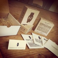 several business cards and envelopes sitting on a wooden table next to an open box