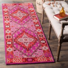 a bright pink rug with an ornate design on the floor next to a white chair