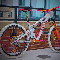 a white and orange bike parked next to a brick building