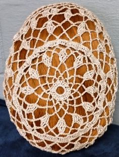 a crochet doily hanging on the wall in front of a blue door