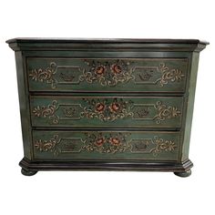 an ornately painted chest of drawers against a white background