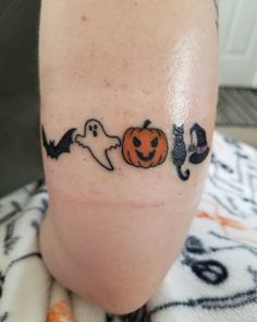 a person with a tattoo on their leg that has three pumpkins and ghost faces