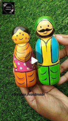 two small wooden dolls are sitting in the grass