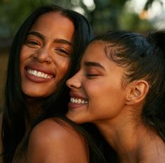 two young women are hugging each other and smiling at the camera while they both have their eyes closed