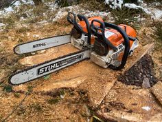 an orange and black chainsaw sitting on top of a tree stump