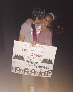 a man and woman standing next to each other holding a sign that says tie and dress