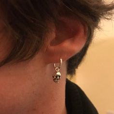 a close up of a person wearing a pair of earrings with a skull on it