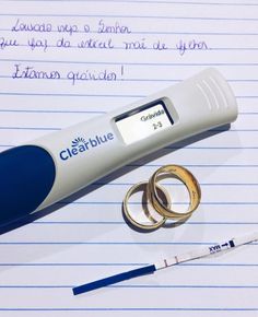 an electronic thermometer and two gold wedding rings on lined paper with writing in spanish