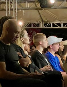 a group of people sitting next to each other in front of a stage with lights