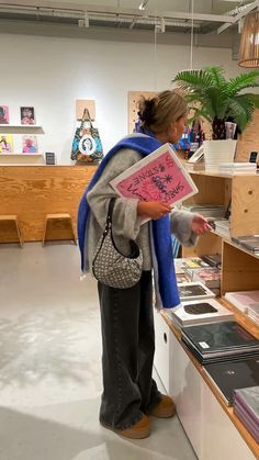 a woman standing in front of a display case holding up a pink piece of paper