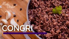 a pot filled with rice next to garlic on top of a wooden cutting board, and the words congri above it