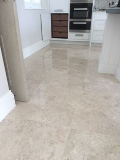 a kitchen with white cabinets and marble flooring