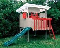 a play house with a slide and climbing frame in the grass next to some trees