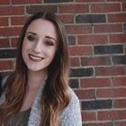 a woman standing in front of a brick wall