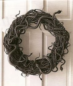 a wreath made out of wire and snakes hanging from it's sides on a door