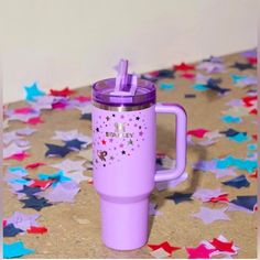 a purple tumbler cup sitting on top of a table covered in confetti