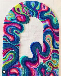 the letter q is made out of yarn and has colorful swirls on it's sides