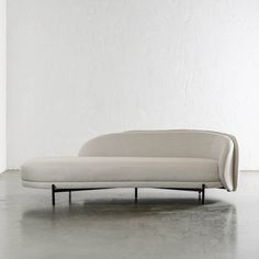 a white couch sitting on top of a cement floor next to a white brick wall