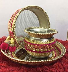 a silver and gold tea set sitting on top of a red rug next to a mirror