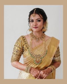 a woman in a yellow sari with jewelry on her neck and hands behind her back