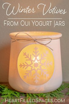 a white candle with a yellow snowflake on it and the words winter votives from ou yogurt jars