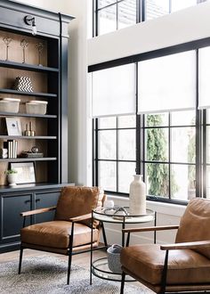 two chairs and a table in front of a bookcase with glass doors on it