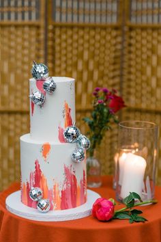 a three tiered cake sitting on top of a table next to a vase with flowers