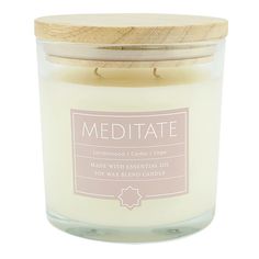 a white candle with a wooden lid and the words meditate written on it in pink