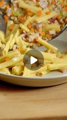 a white plate topped with pasta covered in meat and veggies next to a spoon