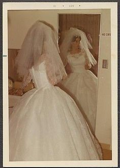 an old photo of two women in wedding dresses looking at each other's reflection