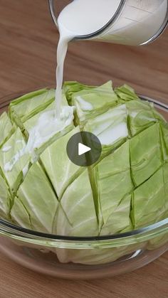 a glass bowl filled with lettuce and milk being poured on top of it