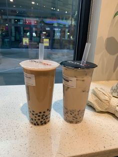 two drinks sitting on top of a counter next to a window