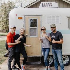 four people standing in front of a trailer