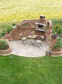 an outdoor kitchen is built into the side of a brick wall and surrounded by green grass