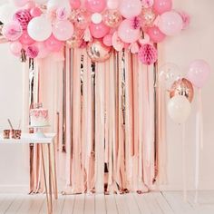 pink and white balloons are hanging from the ceiling