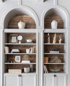 two white bookcases with wooden shelves in the middle and an arch above them