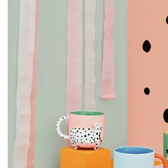 two coffee mugs sitting next to each other in front of wall with polka dots